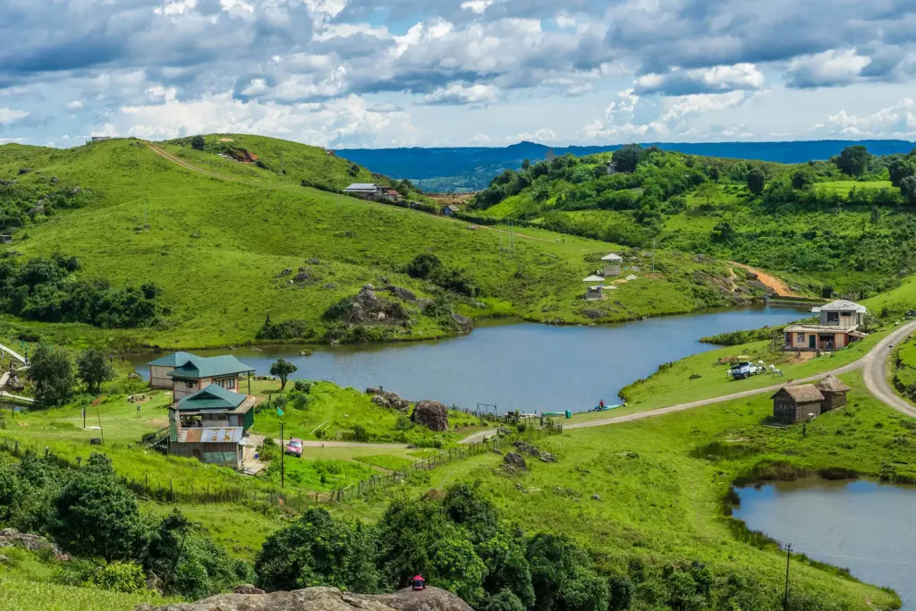 A serene landscape of rolling green hills, lakes, and cottages in Mawphanlur, Meghalaya
