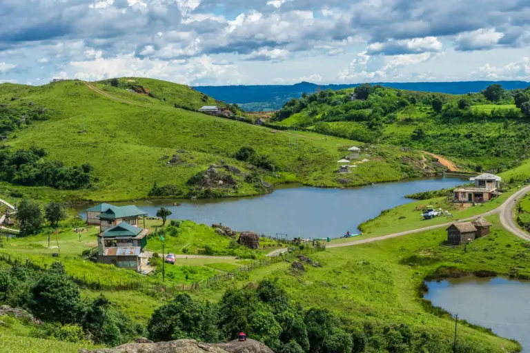 A serene landscape of rolling green hills, lakes, and cottages in Mawphanlur, Meghalaya