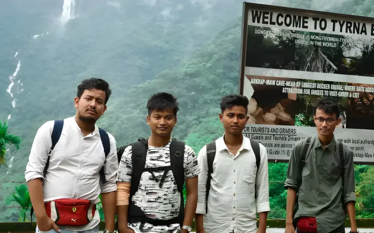Four boys posing near the welcome sign to Nongriat double decker living root bridge Meghalaya