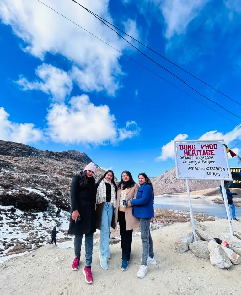 Four women posing near Sela Lake with mountains and a clear blue sky in Arunachal Pradesh