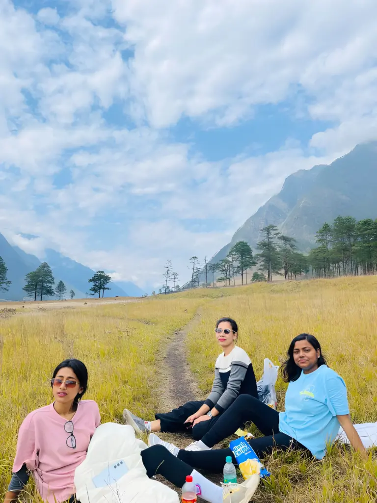 Friends relaxing on a meadow with mountains in the background at Dong Valley
