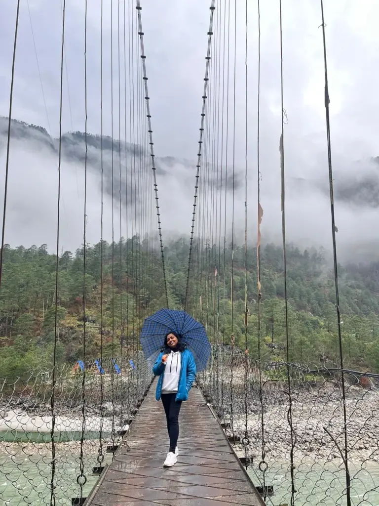 Girl with umbrella standing on a suspension bridge in misty Dong Valley