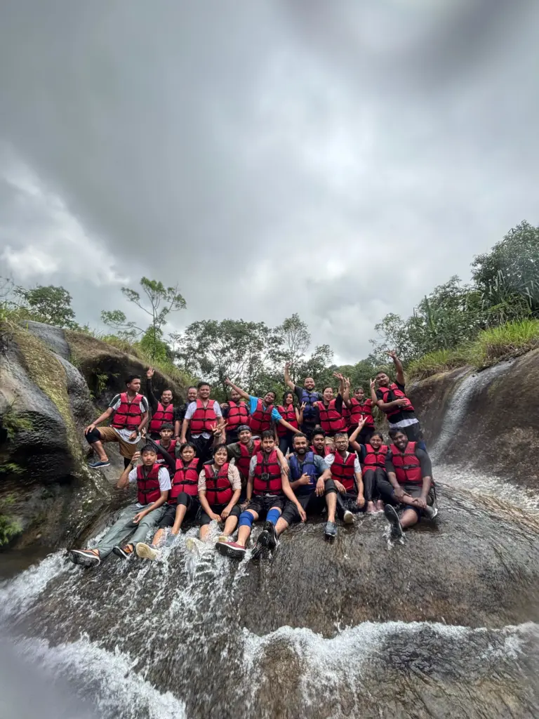 Group of people in life jackets posing on a waterfall rock slide at Mawlyngbna Meghalaya