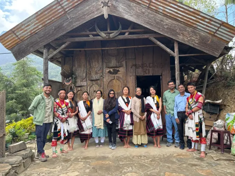 Group photo of visitors and locals in traditional attire at Dzukou Valley