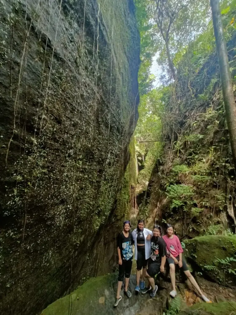 Group posing between towering rock walls during the Split Rock trek at Mawlyngbna, Meghalaya