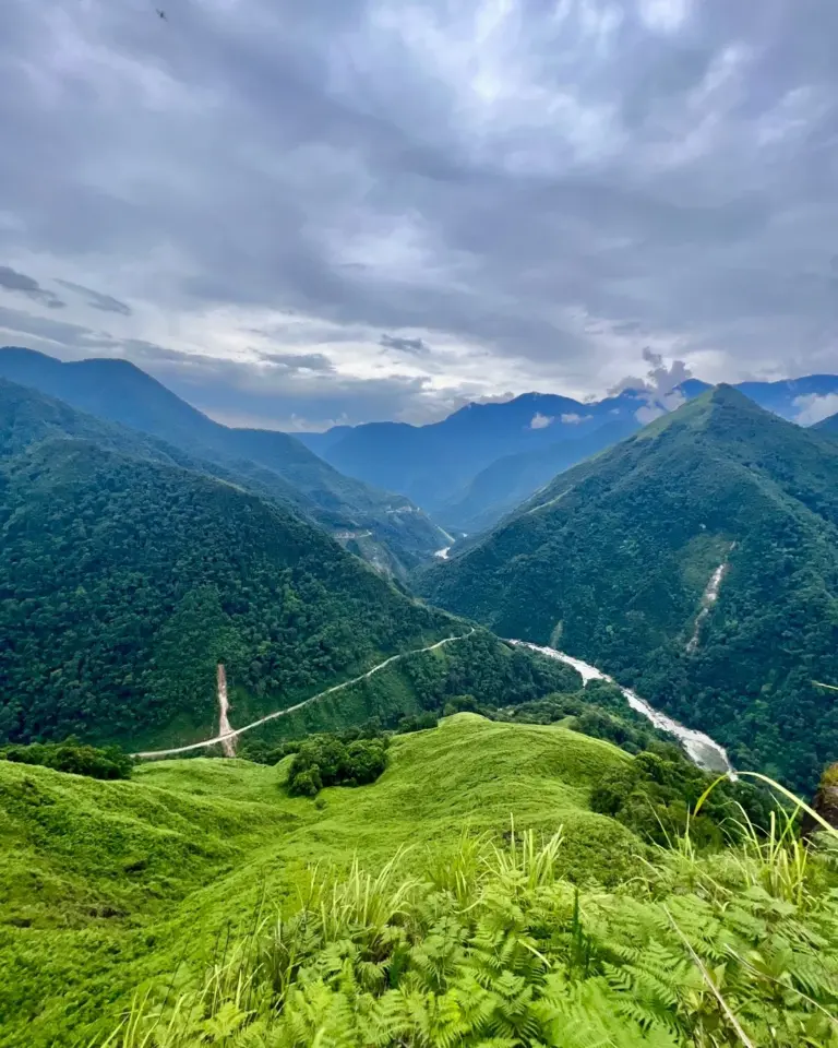 Lush green hills and winding river under cloudy sky in Anini, Arunachal Pradesh