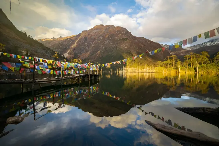 Madhuri Lake with prayer flags and mountain reflection in water