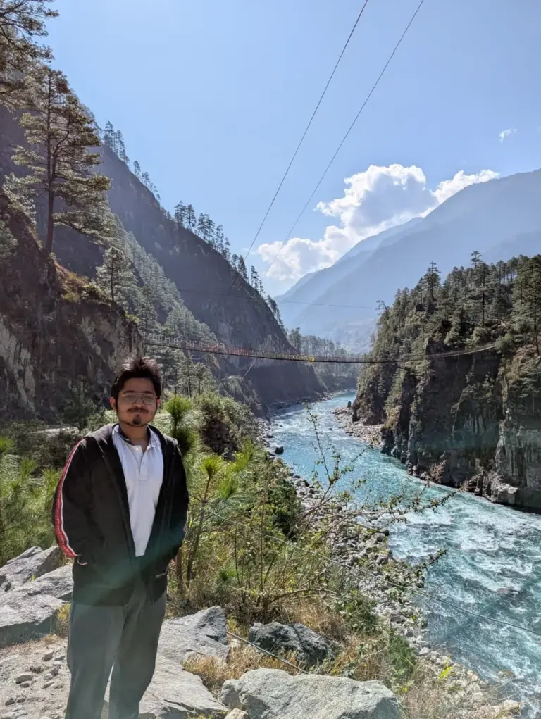 Man posing by a river with mountains in the background at Dong Valley