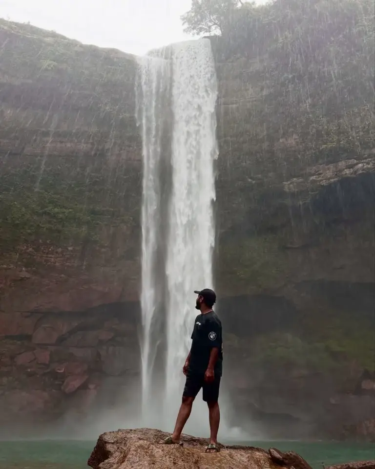 Man standing on a rock in front of Phe Phe Falls in Meghalaya