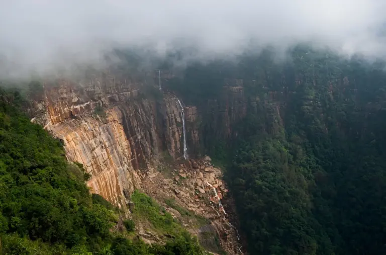 Misty cliffs with Nohkalikai Falls flowing down in Meghalaya