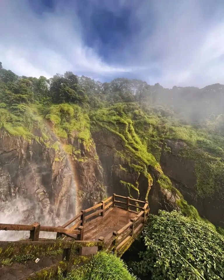 Misty viewpoint with a rainbow near Weinia Falls, surrounded by lush green cliffs in Meghalaya