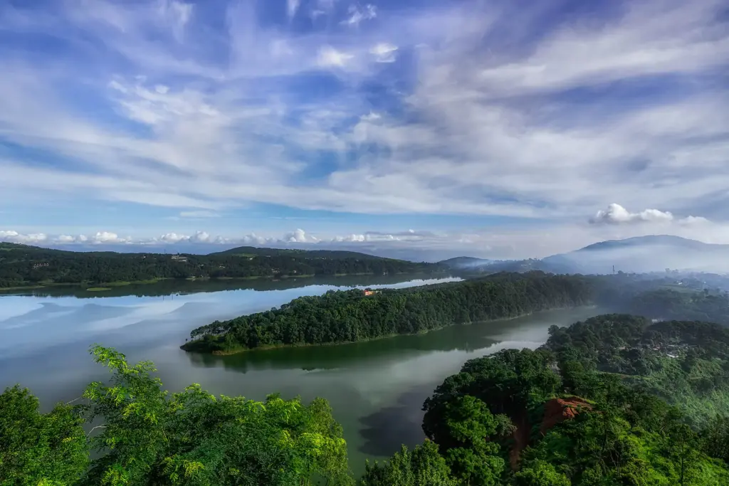 Panoramic view of Umiam Lake with lush green hills and a cloudy sky in Meghalaya