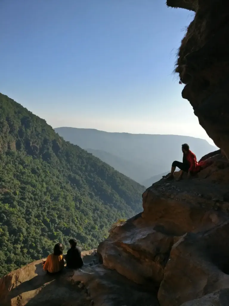 People sitting on rocks overlooking the green hills near Nohkalikai Falls Meghalaya