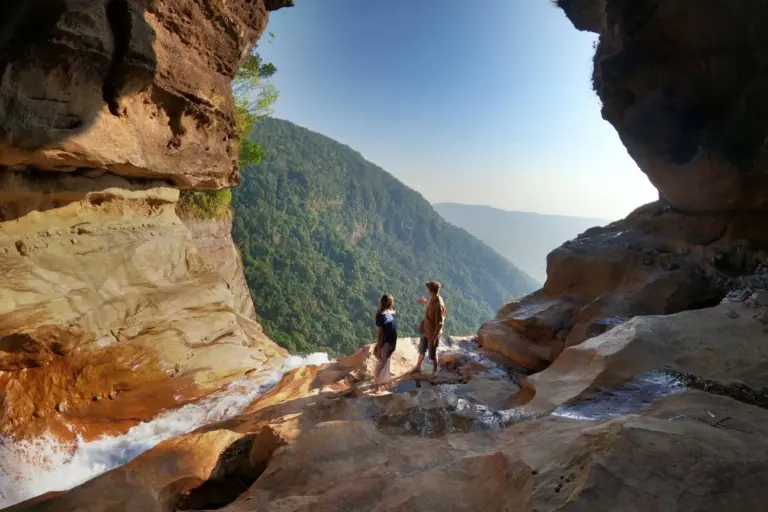 People standing on rocky cliffs with a scenic view at Nohkalikai Falls Meghalaya