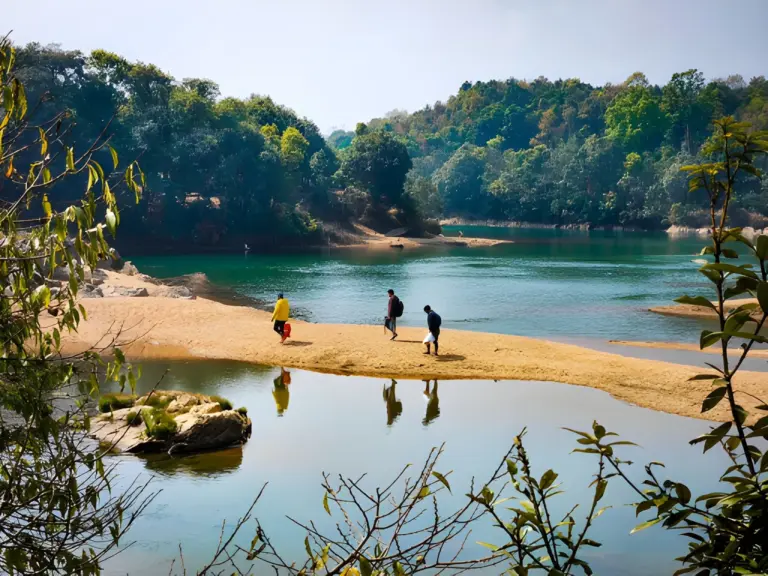 People walking along a sandy stretch beside the river at Nongkhnum Island, Meghalaya