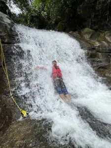 Person enjoying waterfall slide at Mawlyngbna Meghalaya