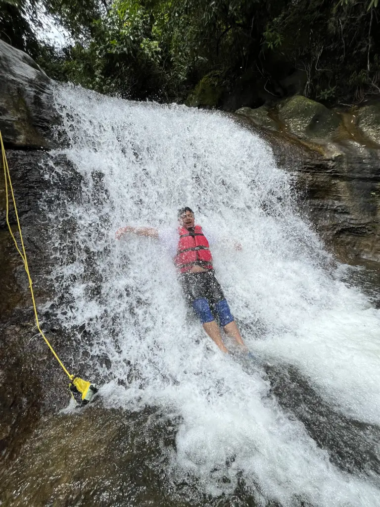 Person enjoying waterfall slide at Mawlyngbna Meghalaya