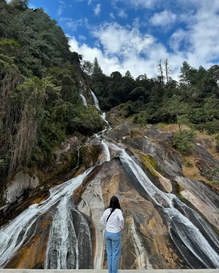 Person looking at a waterfall flowing down rocky slopes in Anini, Arunachal Pradesh