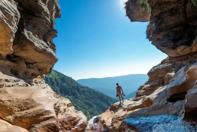 Person standing on rocky cliffs with a scenic view at Nohkalikai Falls Meghalaya