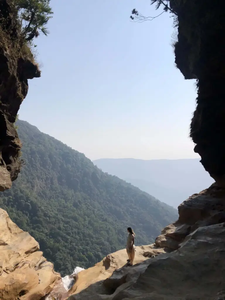 Person standing on rocky edge with valley view at Nohkalikai Falls Meghalaya