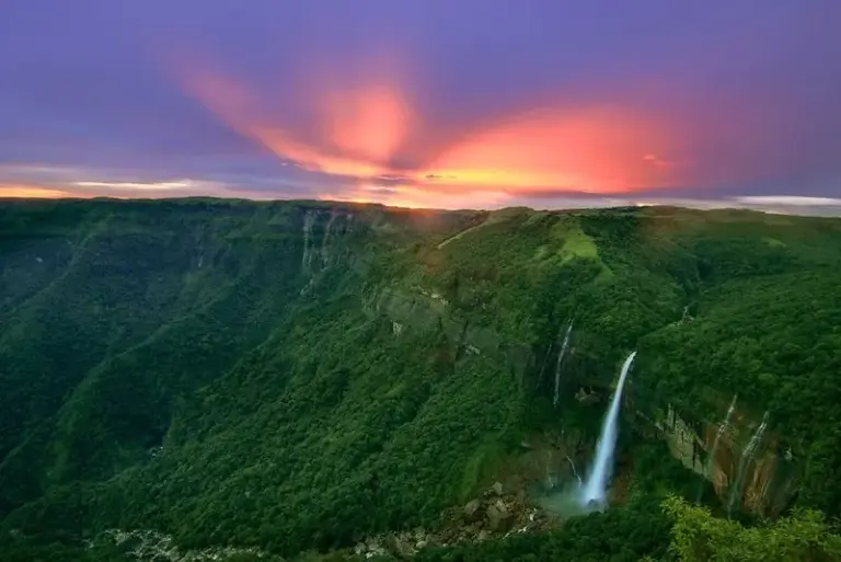 Sunset view of Nohkalikai Falls surrounded by lush green hills in Meghalaya