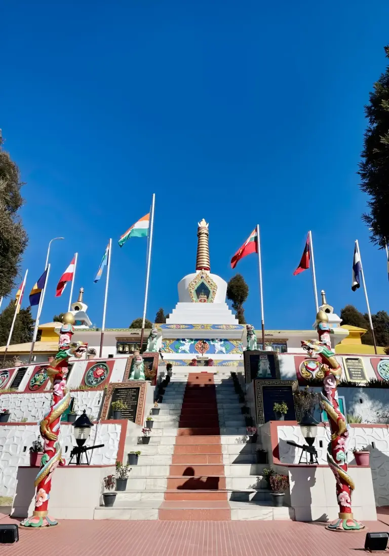 Tawang War Memorial with flags and central stupa under clear blue sky