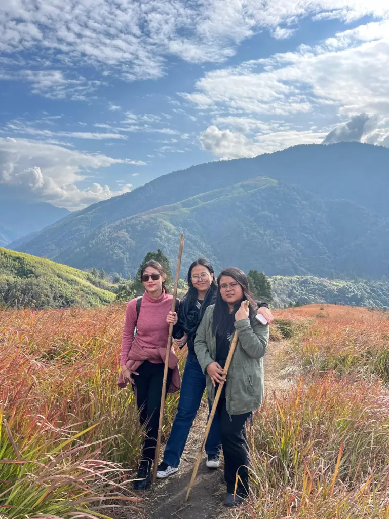 Three women hiking through grassy hills in Anini, Arunachal Pradesh