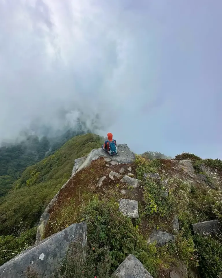 Trekker sitting on a rocky cliff at Mount Japfu