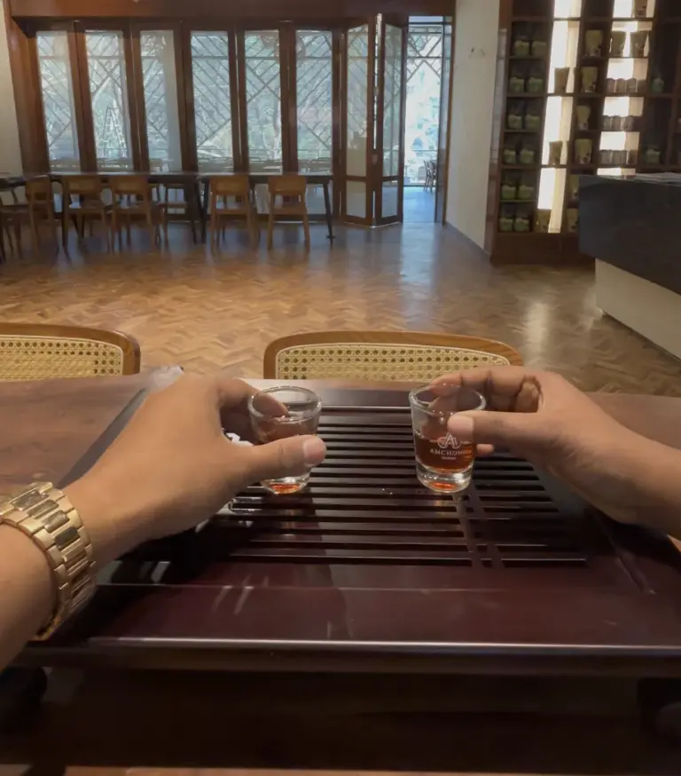Two people holding small cups of tea during a tasting at a tea garden in Guwahati Assam