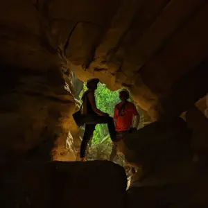 Two people silhouetted inside a rocky cave at Split Rock trek, Mawlyngbna, Meghalaya