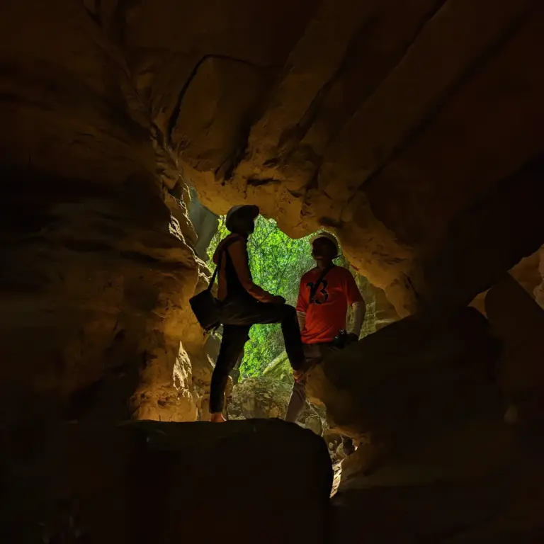 Two people silhouetted inside a rocky cave at Split Rock trek, Mawlyngbna, Meghalaya