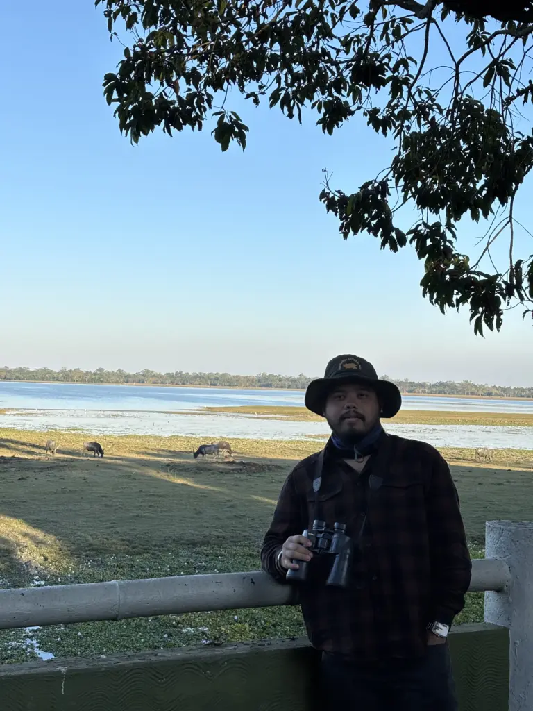Visitor with binoculars overlooking wildlife and wetlands in Kaziranga National Park Assam