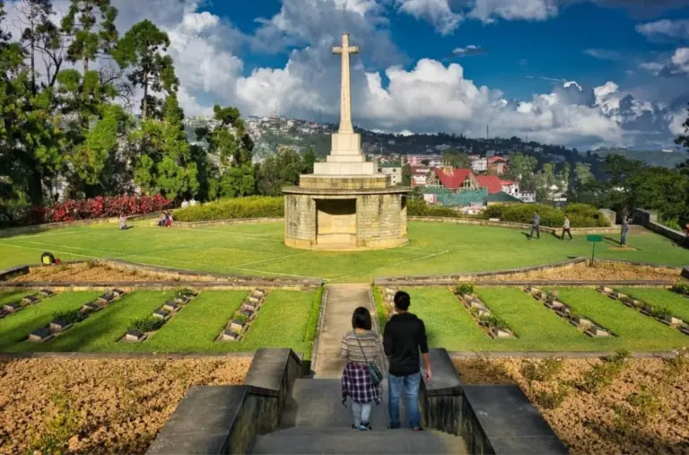 Visitors walking toward memorial cross at Kohima War Cemetery