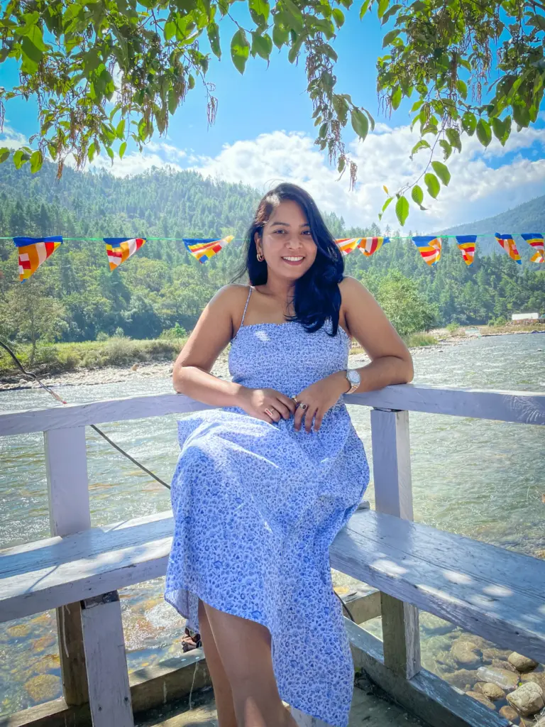 Woman by the river with hills and flags in Sangti Valley, Arunachal Pradesh
