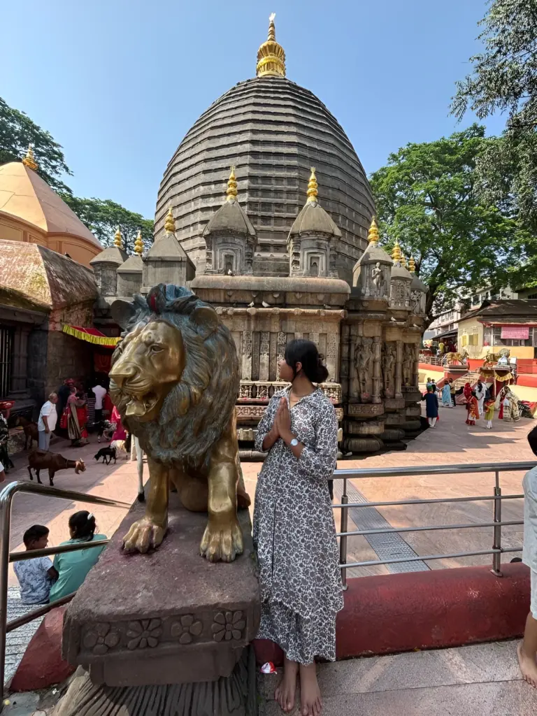 Woman offering prayers beside lion statue at Maa Kamakhya Temple, Assam