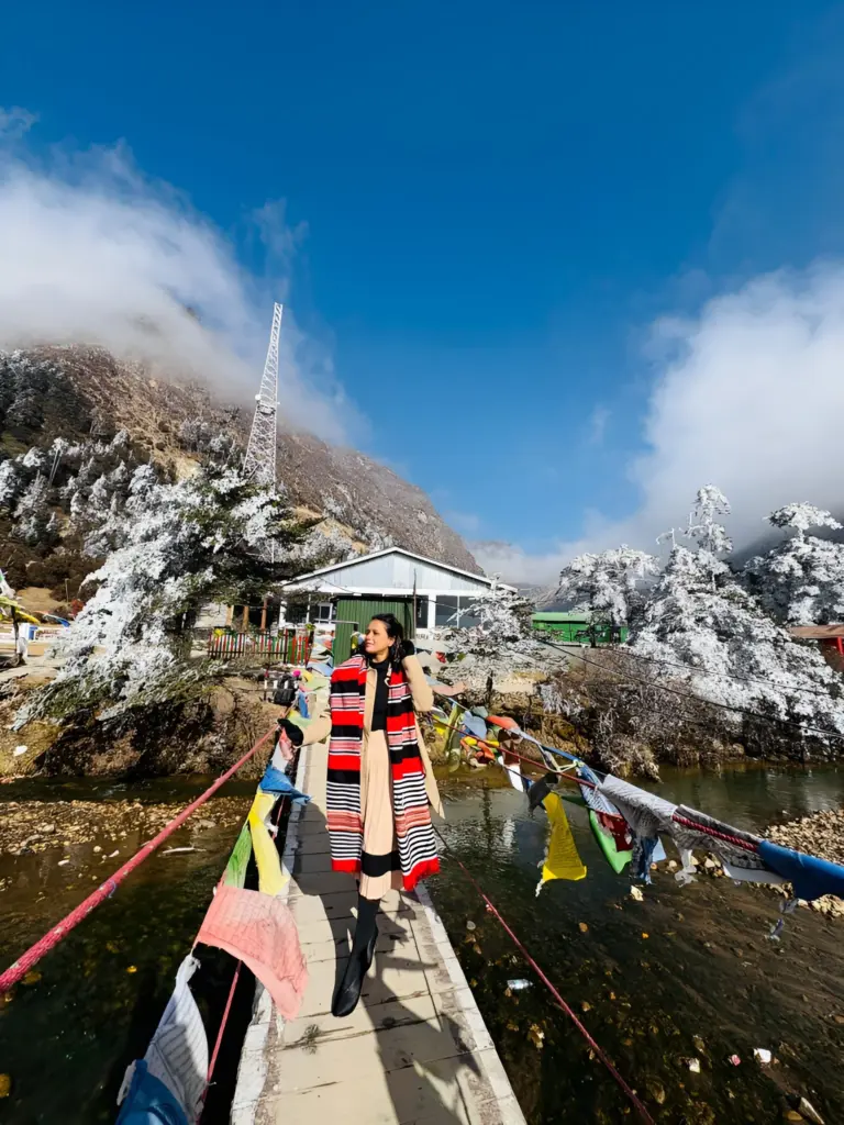 Woman on a bridge with prayer flags at snowy Sela Pass, Arunachal Pradesh