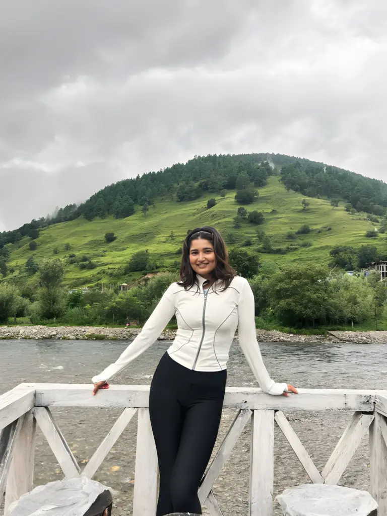 Woman posing by a riverside with green hills in the background at Sangti Valley