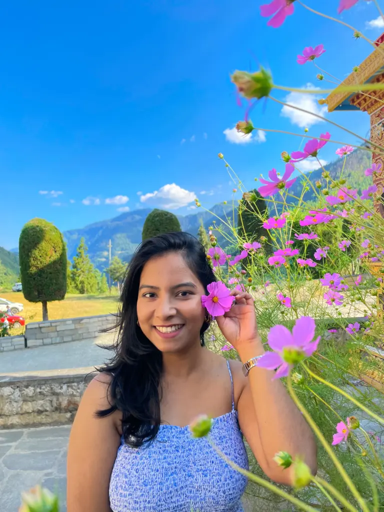Woman smiling with a pink flower by her ear in Sangti Valley, Arunachal Pradesh