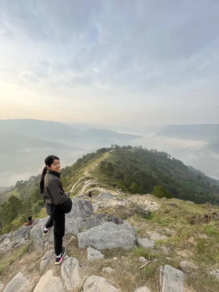 Woman standing on a rocky hilltop with misty valleys in Nongjrong, Meghalaya