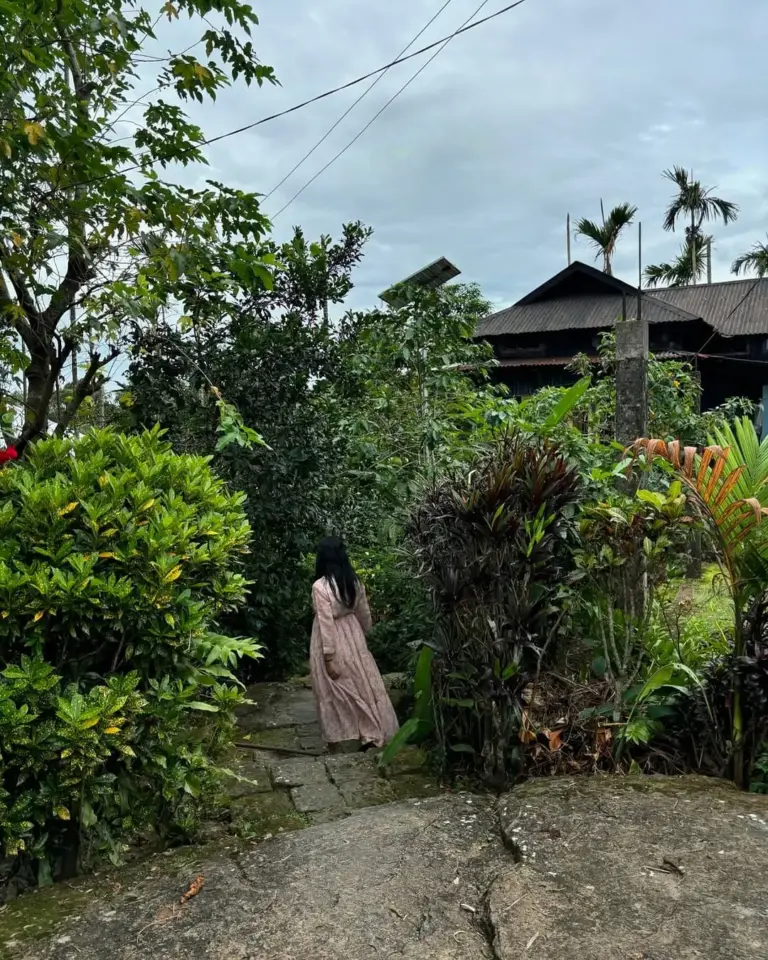 Woman walking on a stone path surrounded by lush greenery in Mawlynnong, Meghalaya