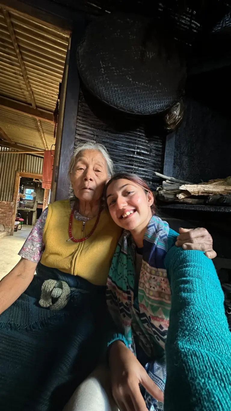 Traveller sharing a smile with an elderly Naga woman in a traditional kitchen