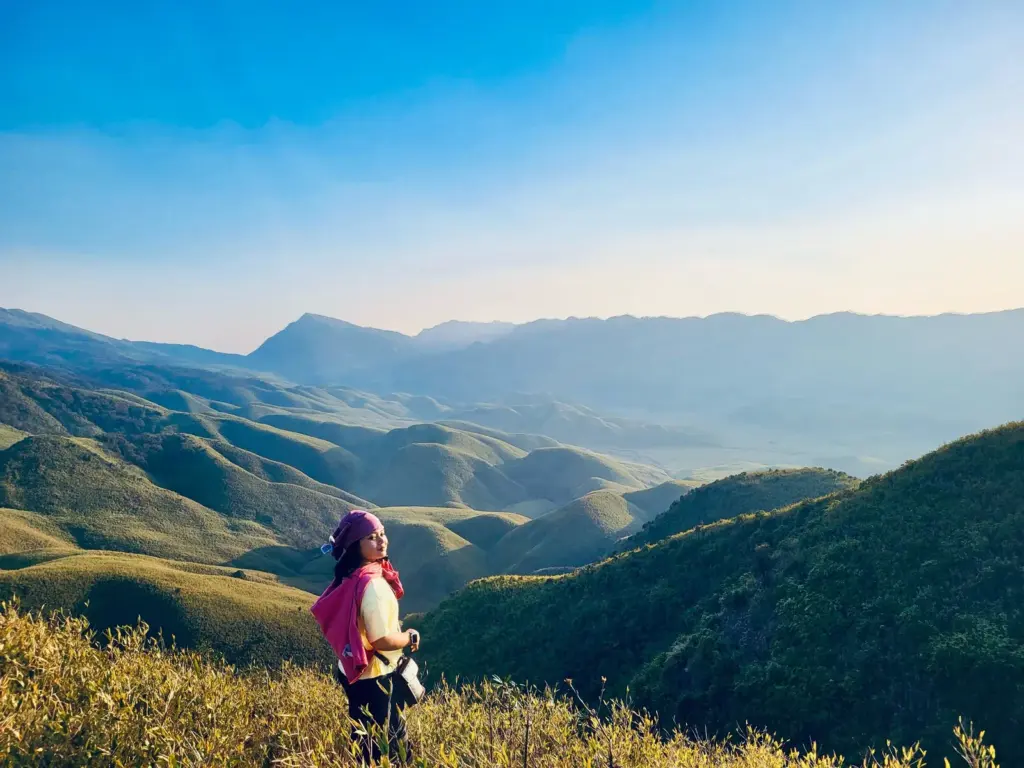 A girl enjoying the scenic view of rolling green hills in Dzukou Valley, Nagaland