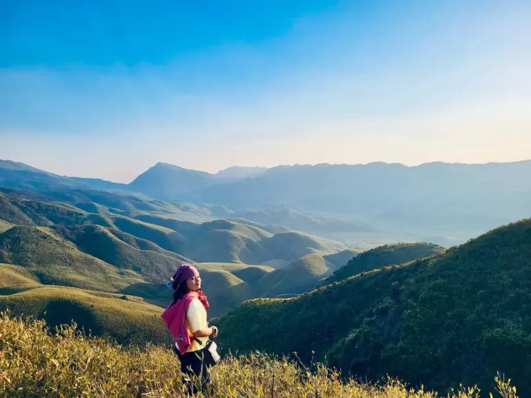 A girl enjoying the scenic view of rolling green hills in Dzukou Valley, Nagaland