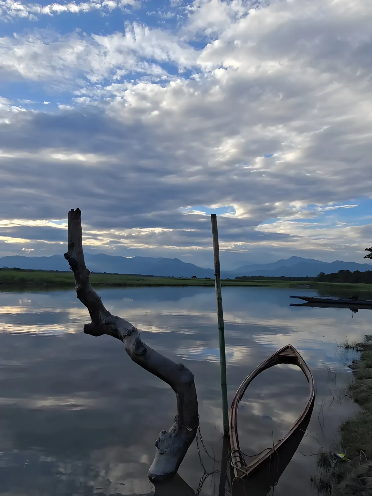 A serene view of Majuli with a traditional wooden boat moored along the calm riverside