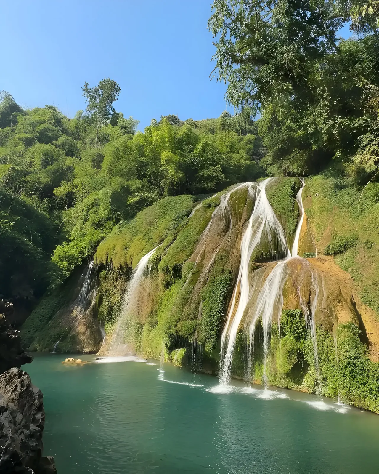 Krem Chympe Cave waterfalls cascading into a turquoise pool, Meghalaya