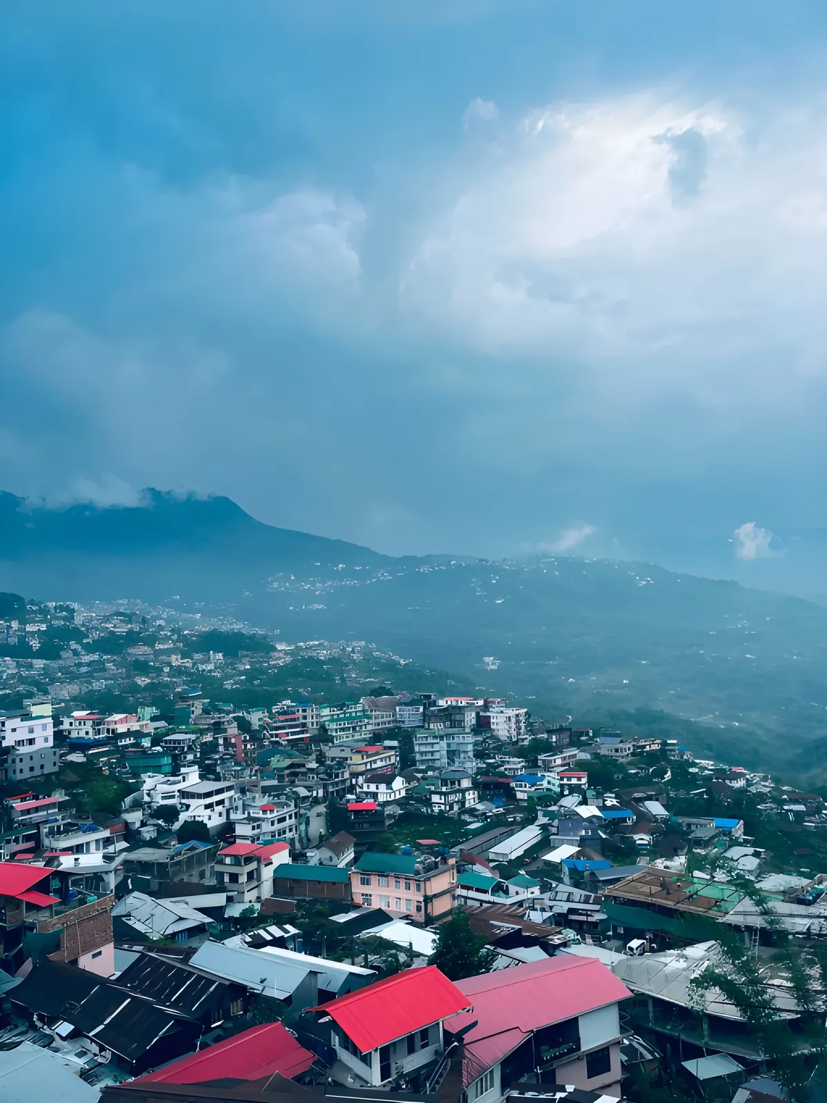 Panoramic view of Kohima, Nagaland, with colorful hillside homes, mist-covered mountains