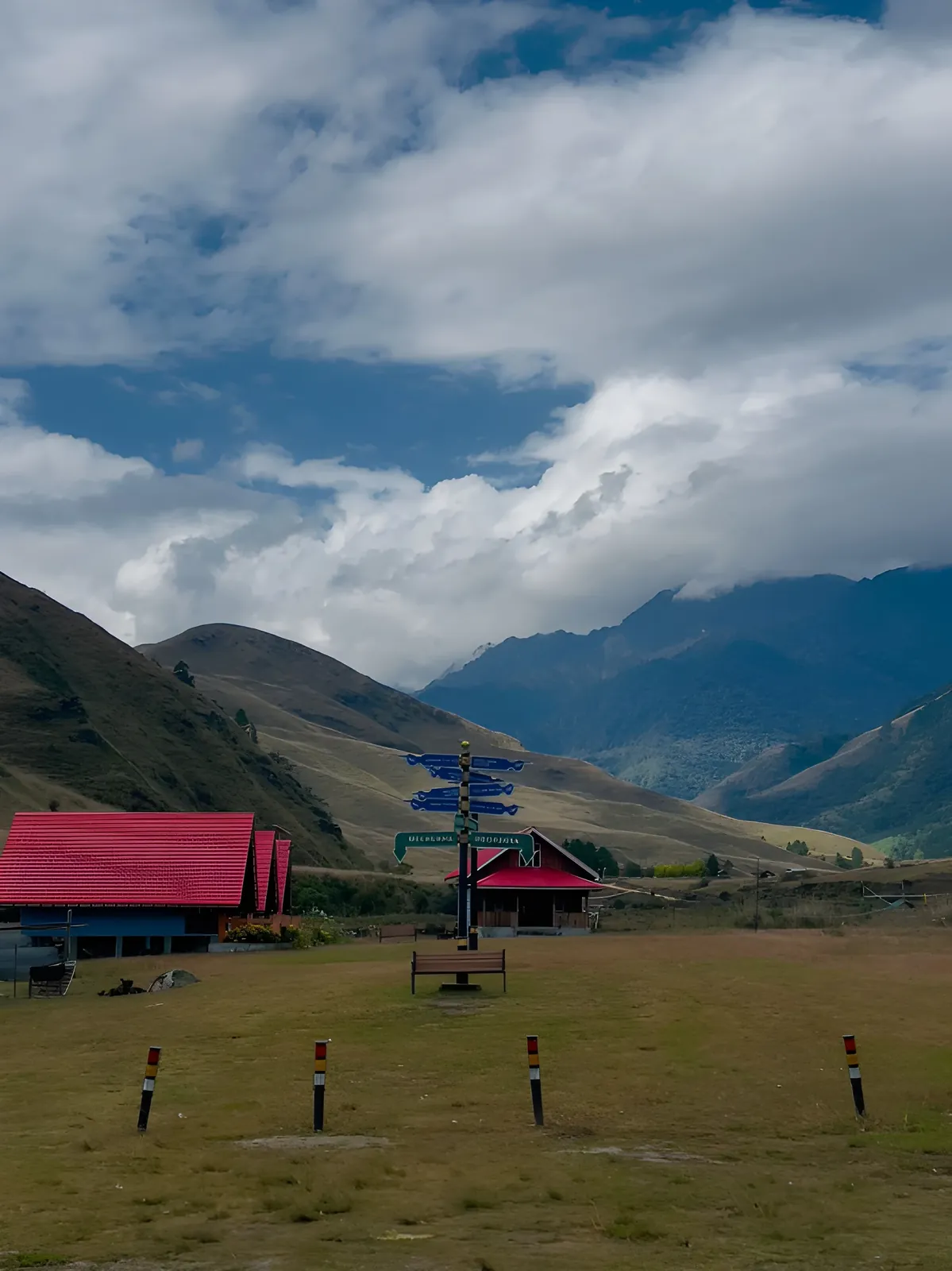 Scenic view of Mechuka, Arunachal Pradesh, with red-roofed buildings, rolling green hills, distant mountains