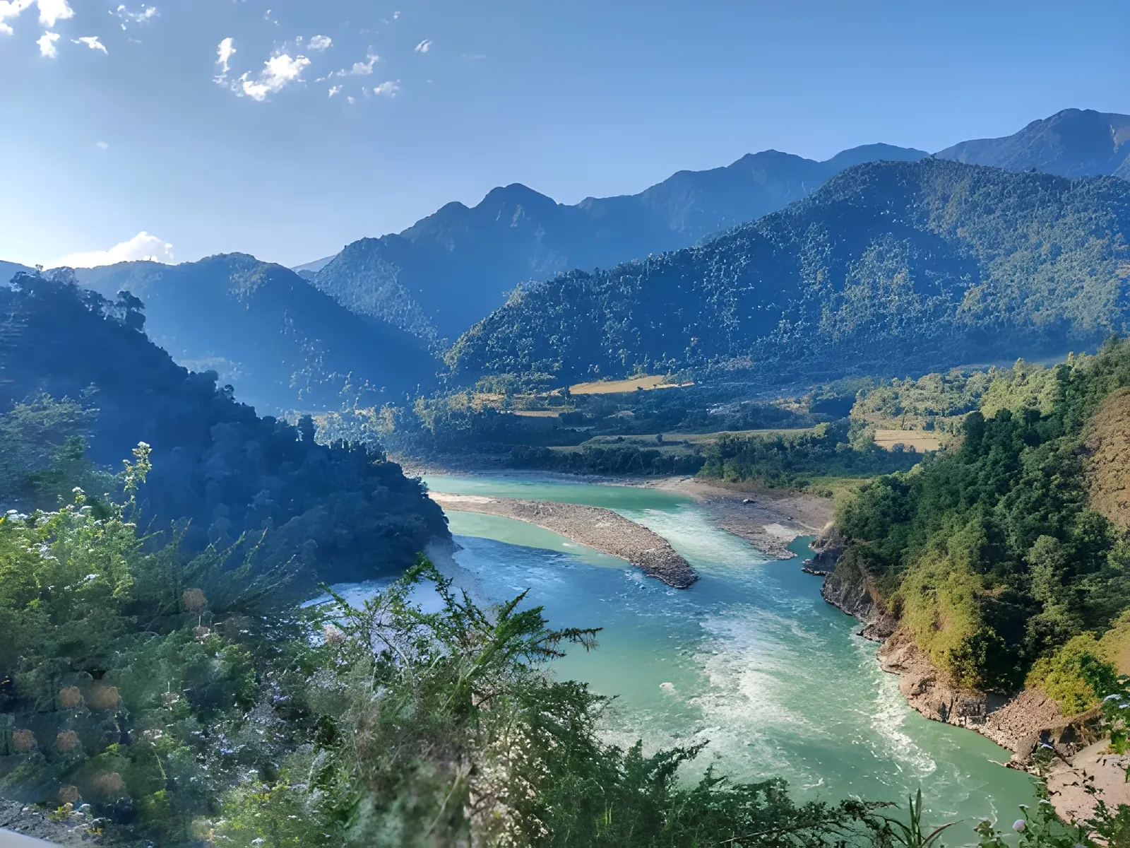 Siang River winding through lush green mountains near Pasighat under a clear blue sky