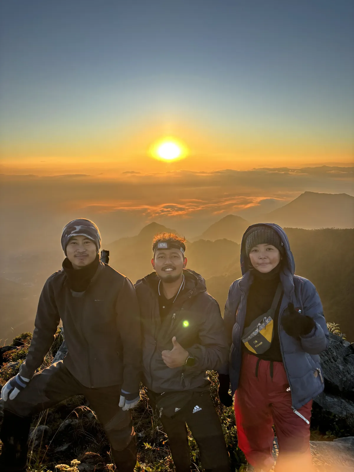 Three people at Japhu Peak during sunrise